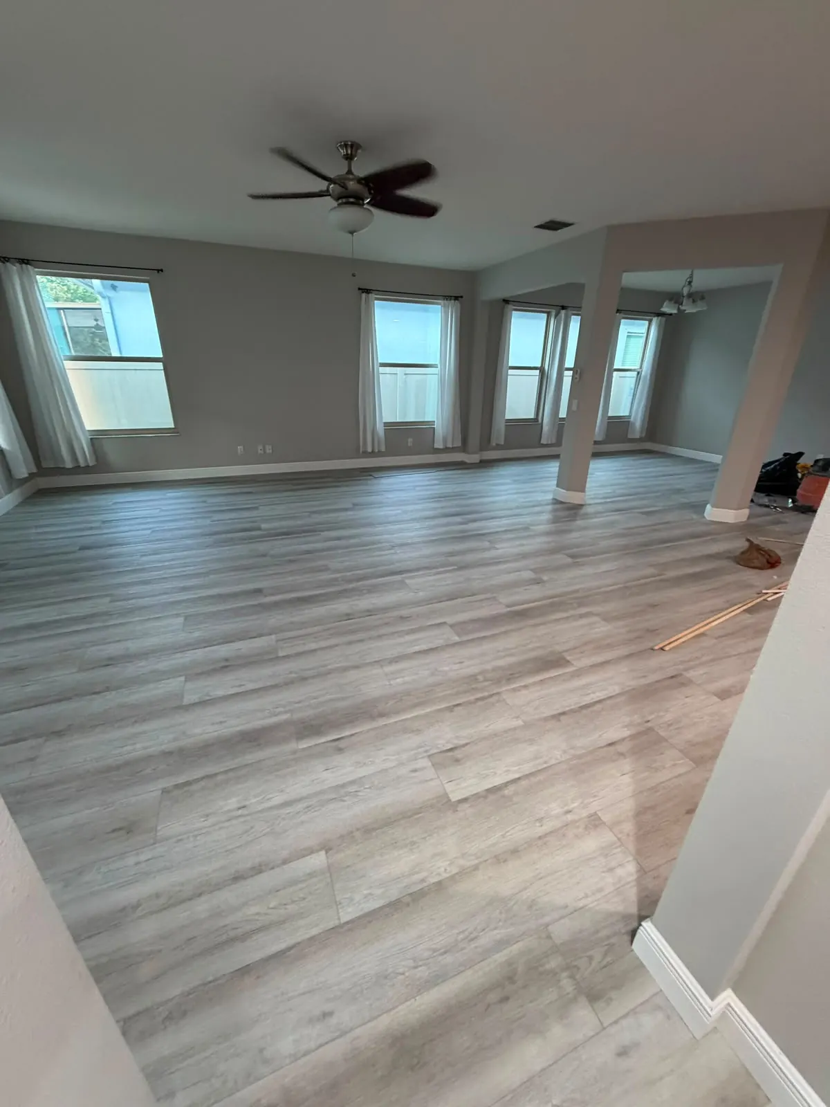 Large living room with gray vinyl plank flooring and white baseboards along the walls