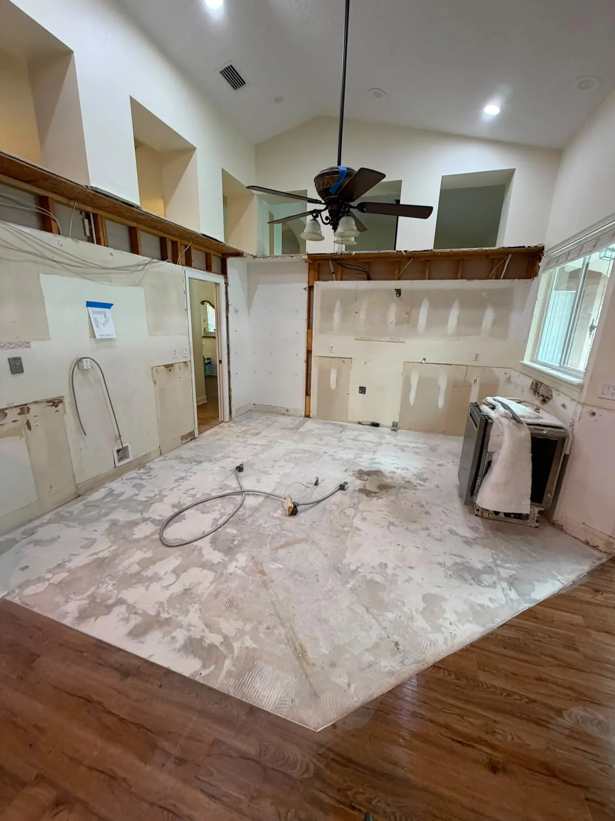 Kitchen with the old flooring removed, showing the exposed subfloor and adhesive residue