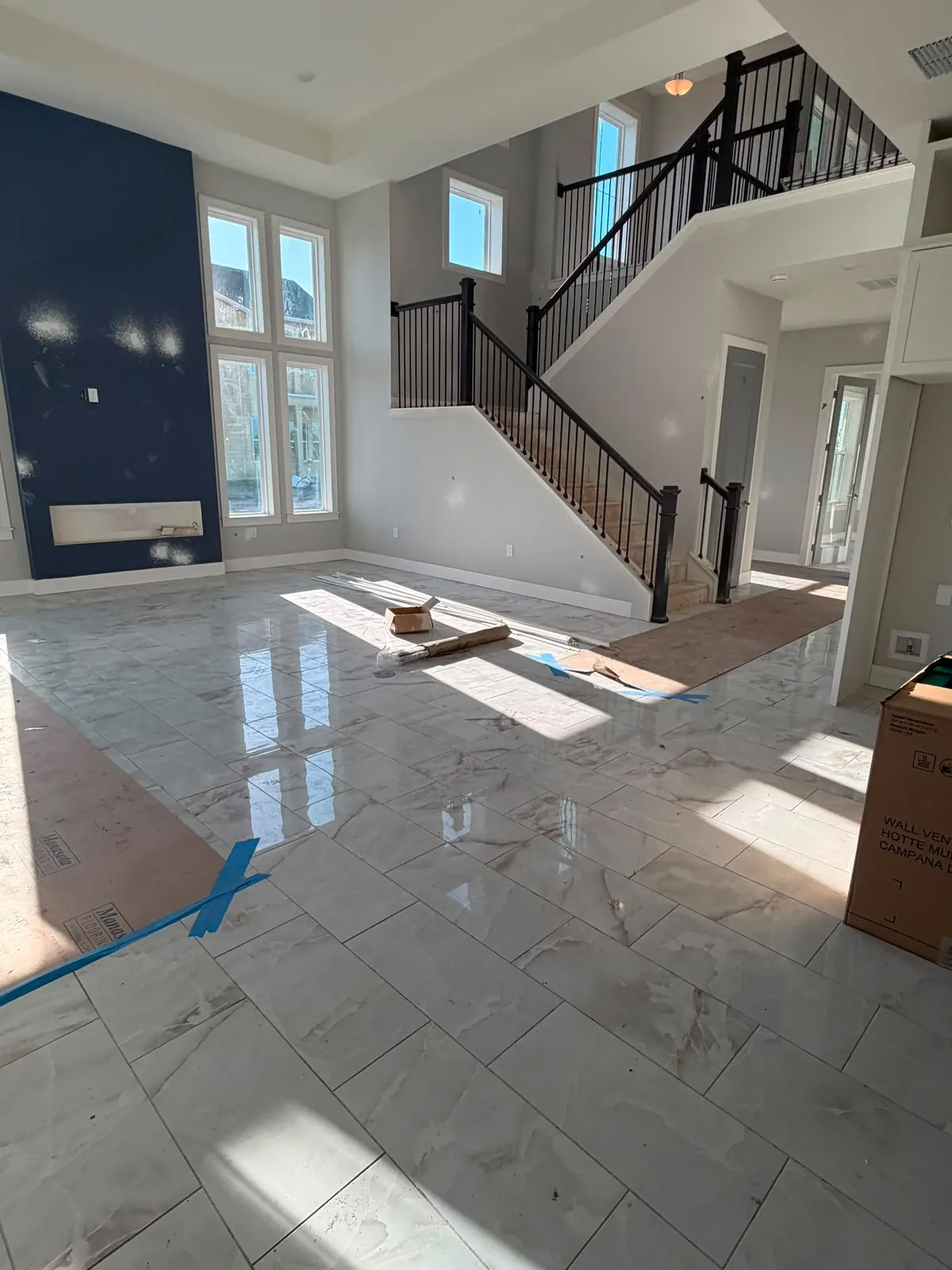 Large-format marble-look tile floor in a two-story entry with a staircase