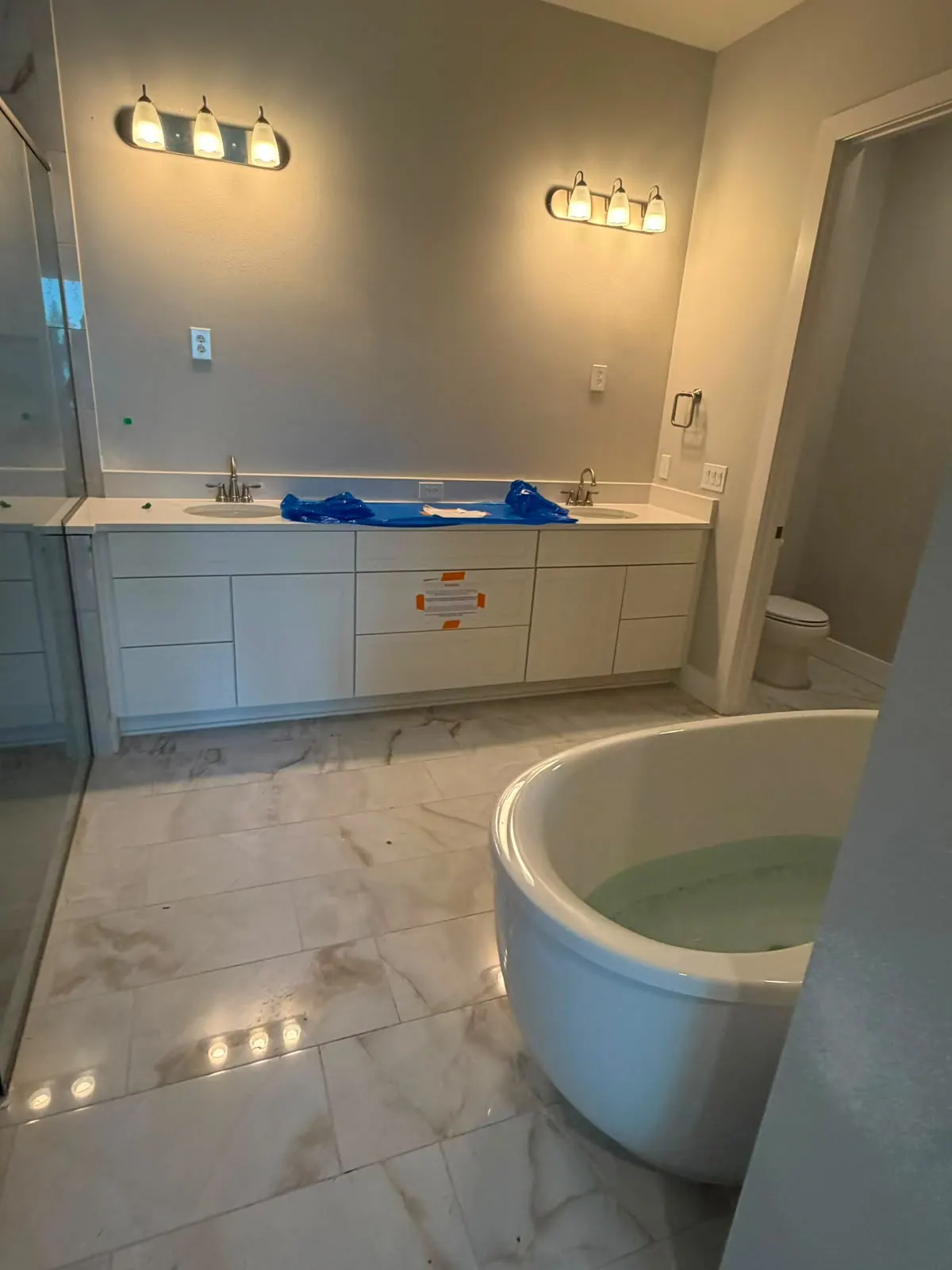 Bathroom with marble-look floor tile around a freestanding tub and a double vanity